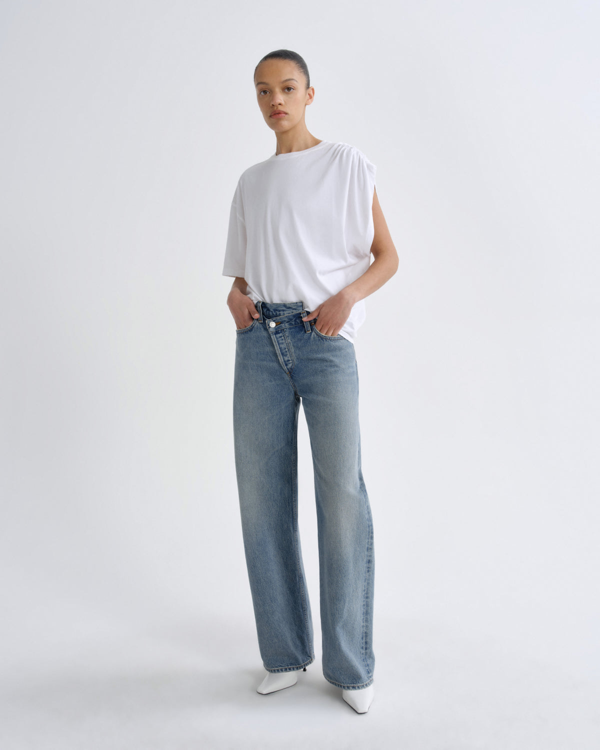 Person wearing a white t-shirt and blue jeans on a plain background