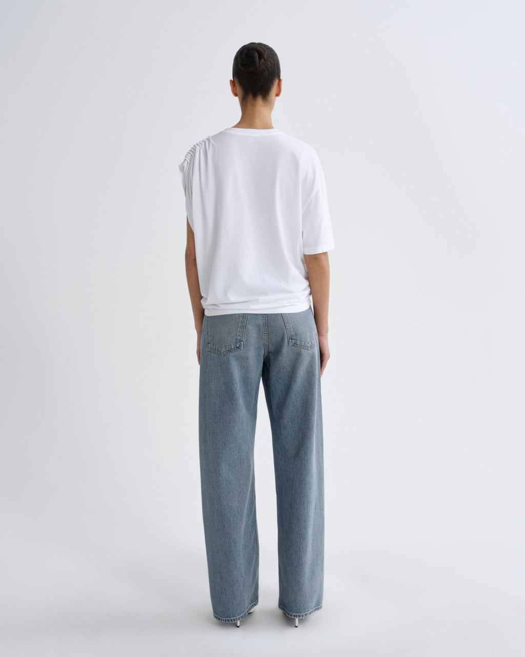 Person wearing a white top and light blue pants on a plain background