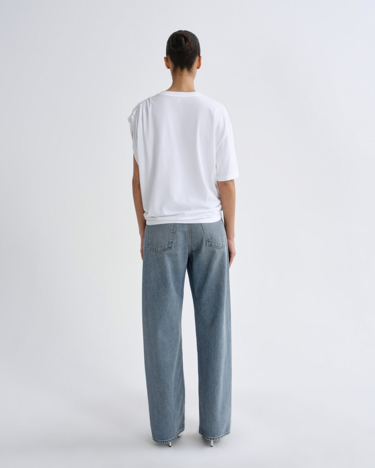 Person wearing a white top and light blue pants on a plain background