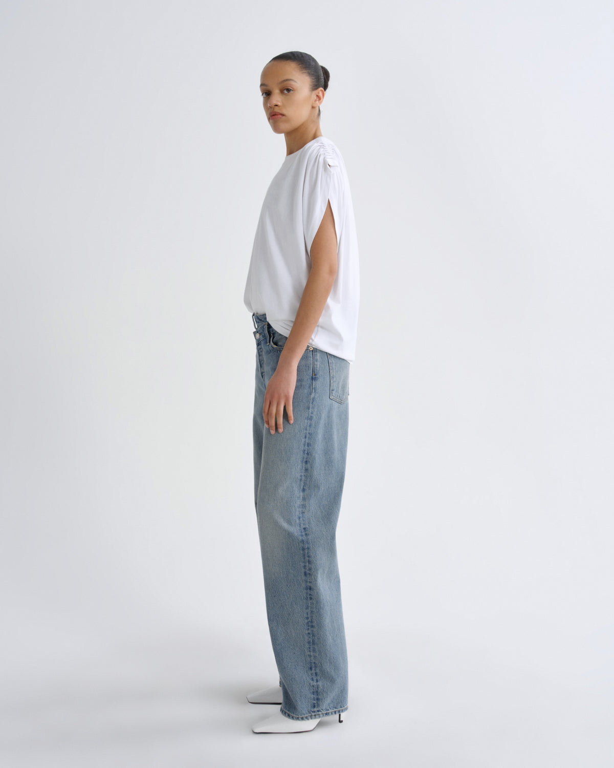 Person wearing a white top and blue jeans on a plain background