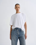 Person wearing a white t-shirt and blue jeans on a plain background