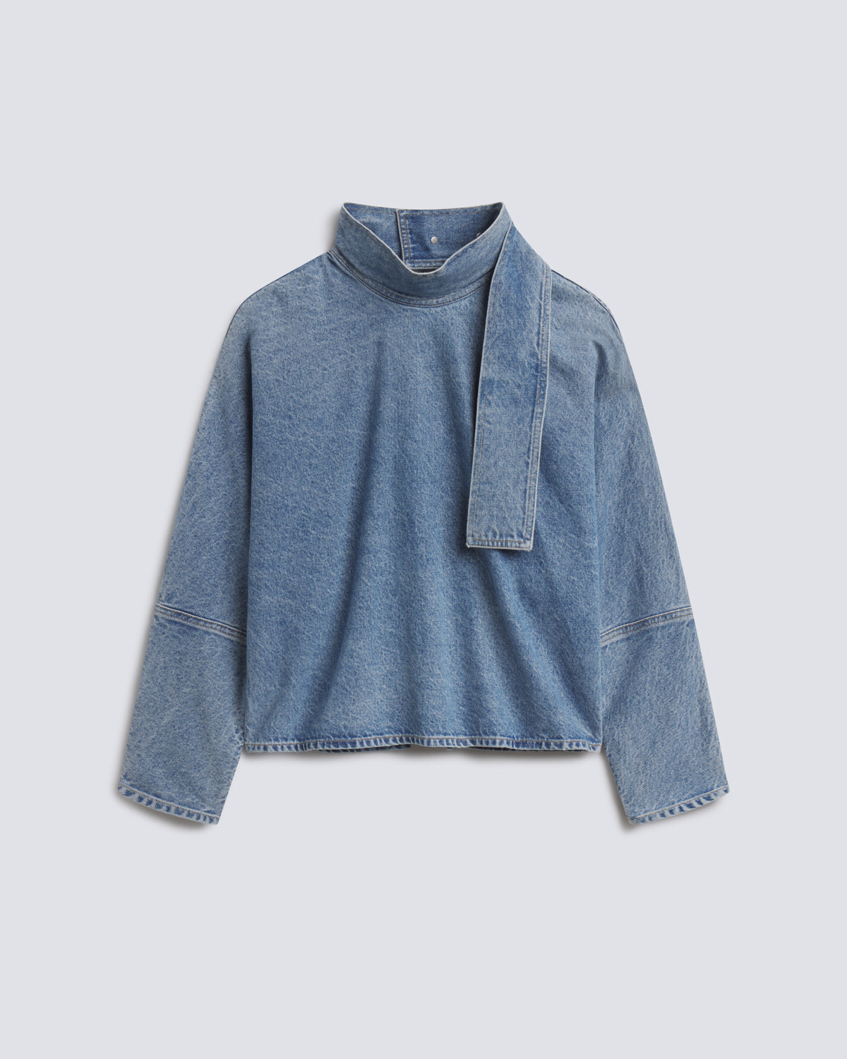 A light blue denim long-sleeve top with a high mock neck and a wide tie detail at the collar, displayed flat against a light gray background.