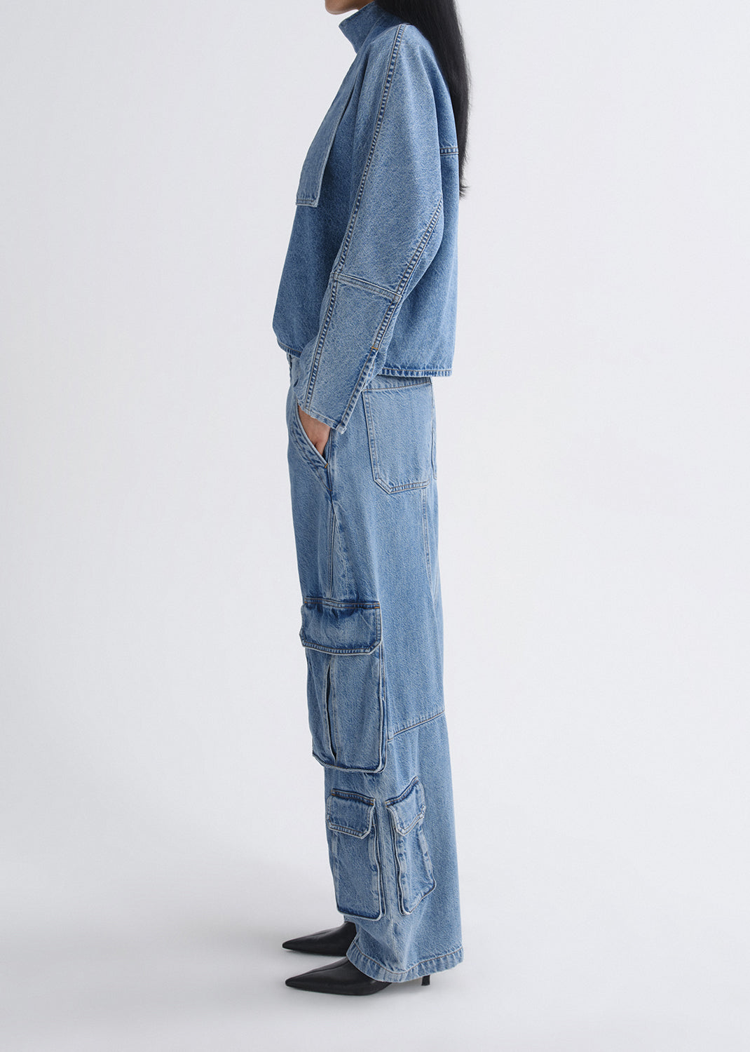 Person wearing a blue denim outfit on a grey background
