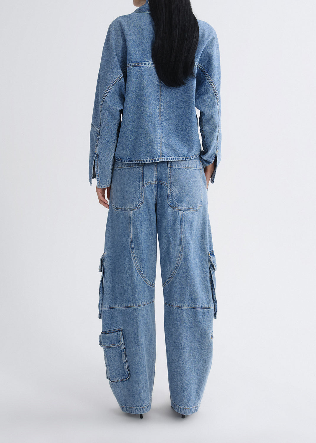 Person wearing a blue denim outfit on a grey background