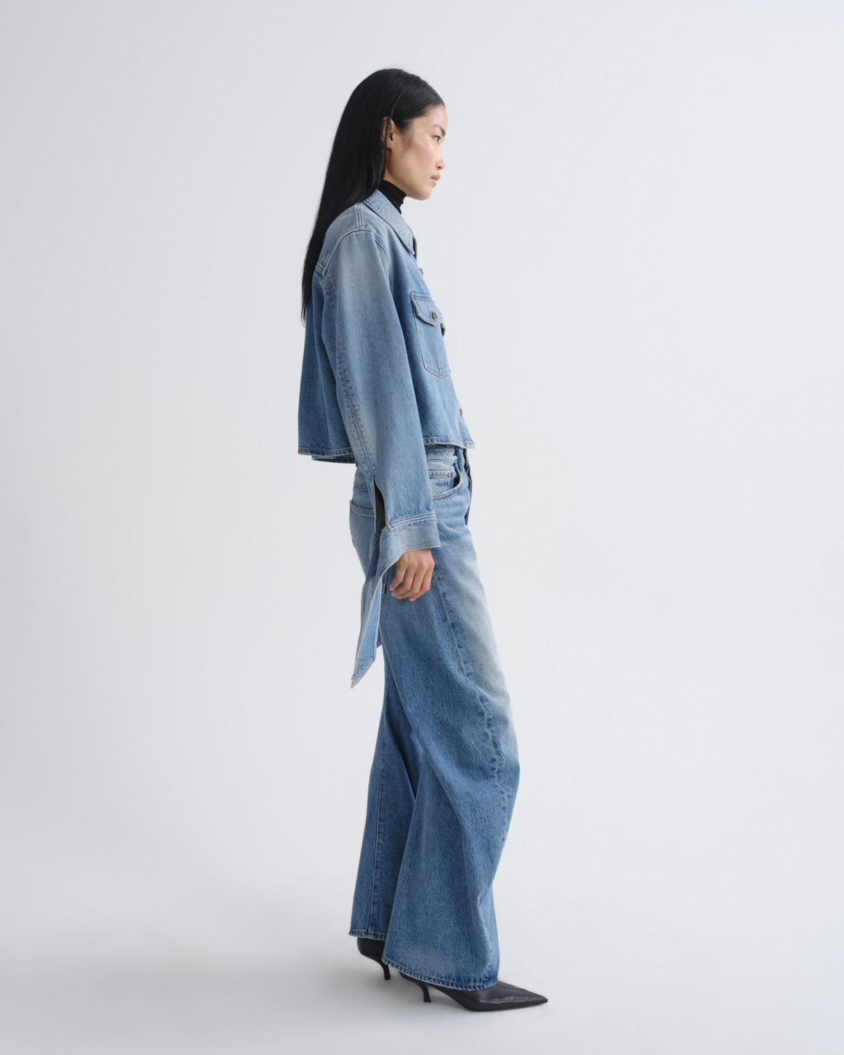 Person wearing a denim jacket and jeans on a white background