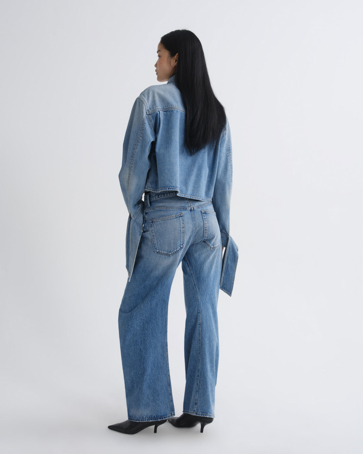 Person wearing a blue denim outfit on a white background