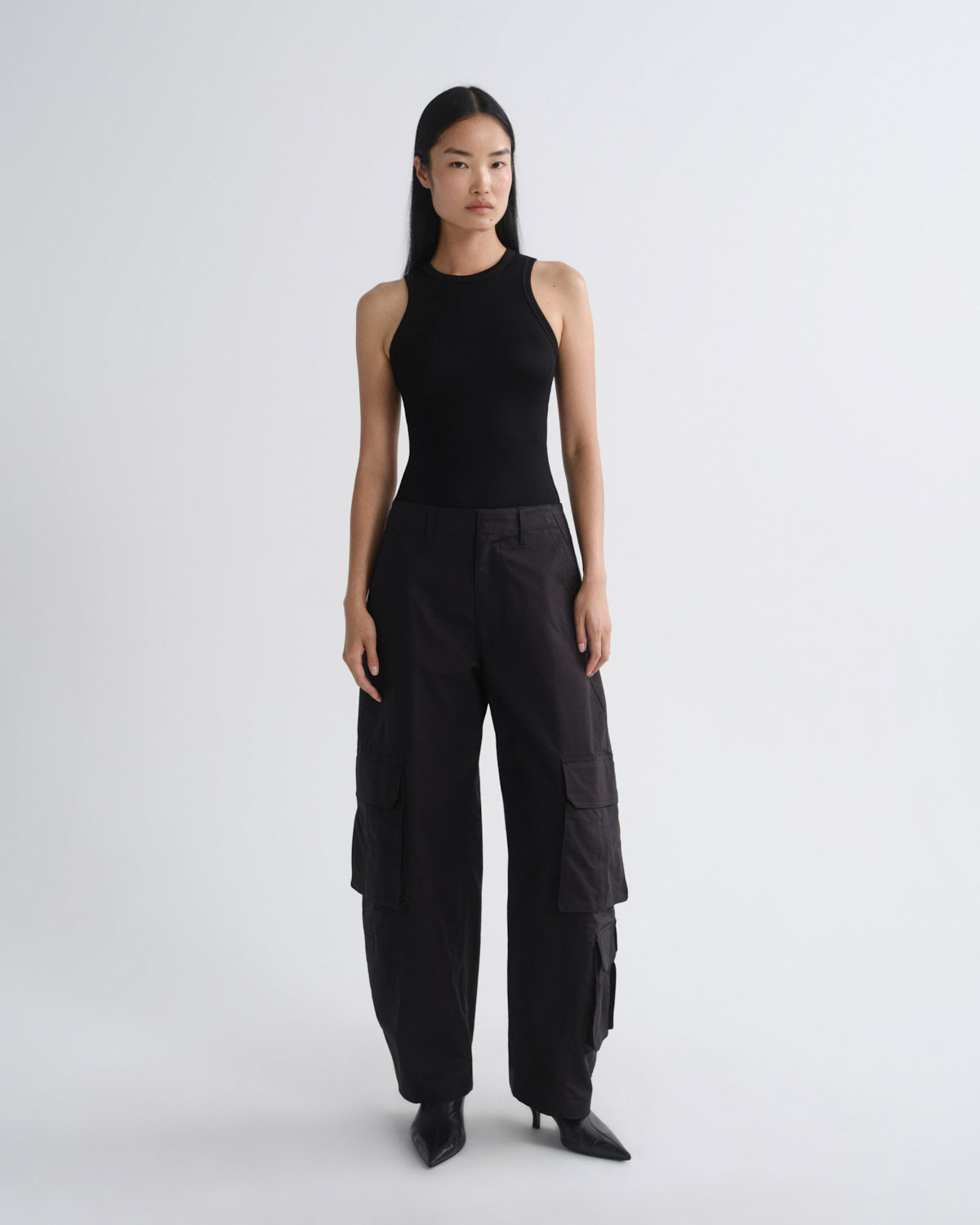 Person wearing a black sleeveless top and black cargo pants on a white background