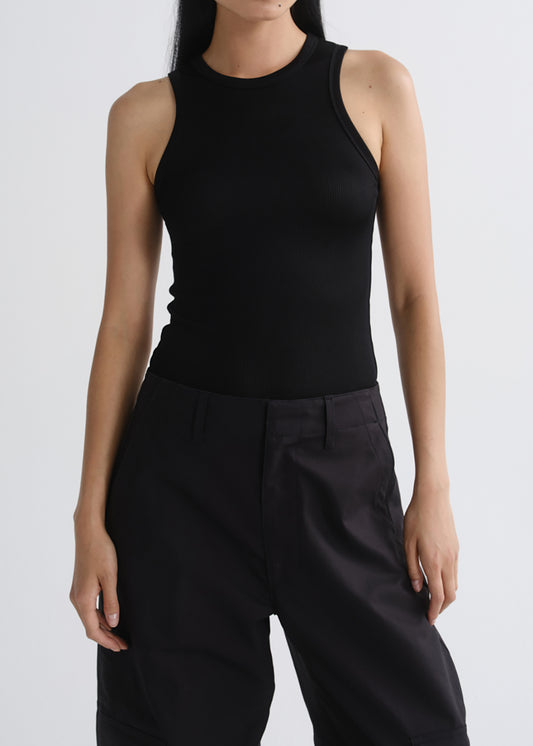 A model wearing a black sleeveless ribbed tank top and black wide-leg trousers, shown from the neck down against a grey background.