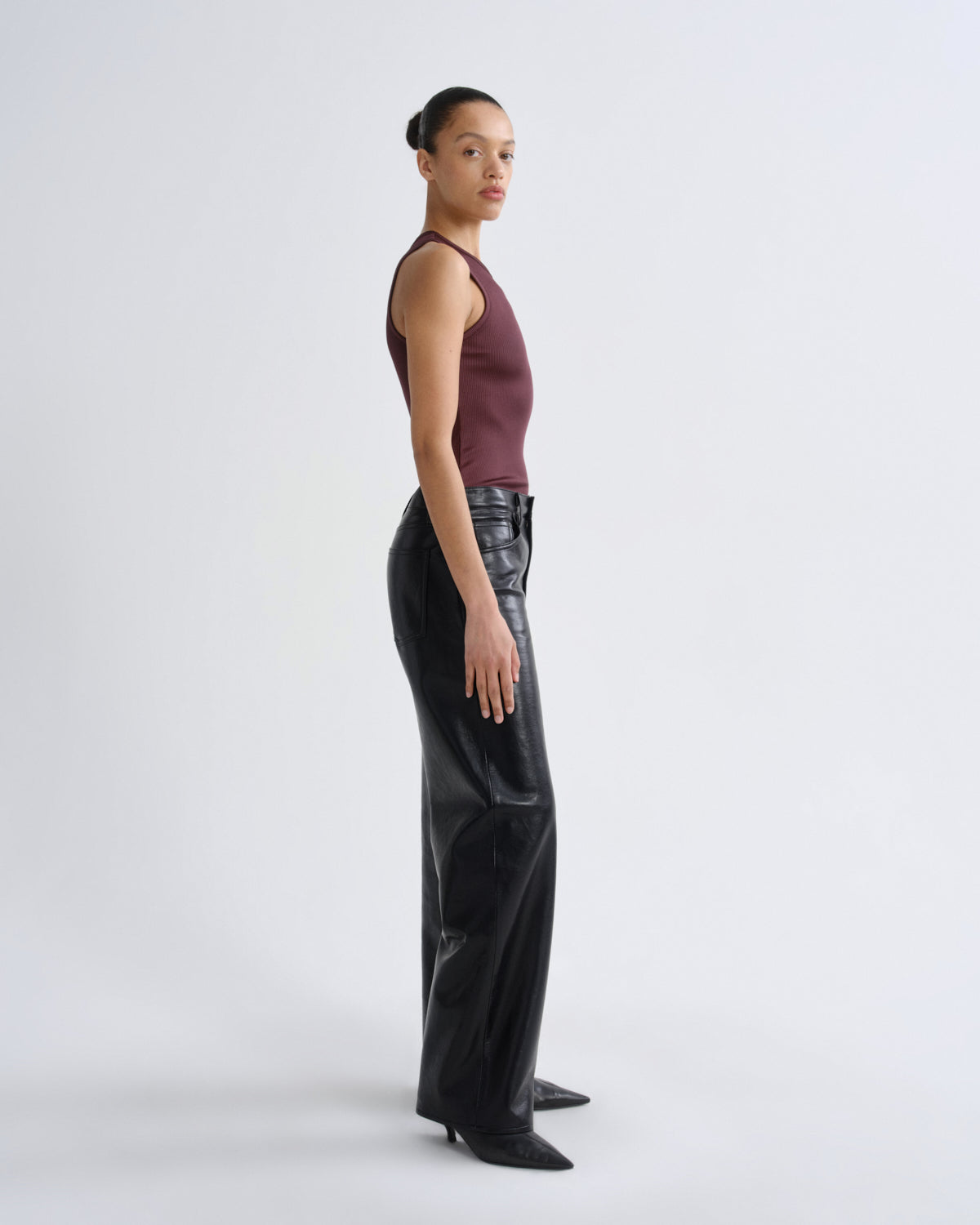 Person wearing a burgundy top and black leather pants on a white background