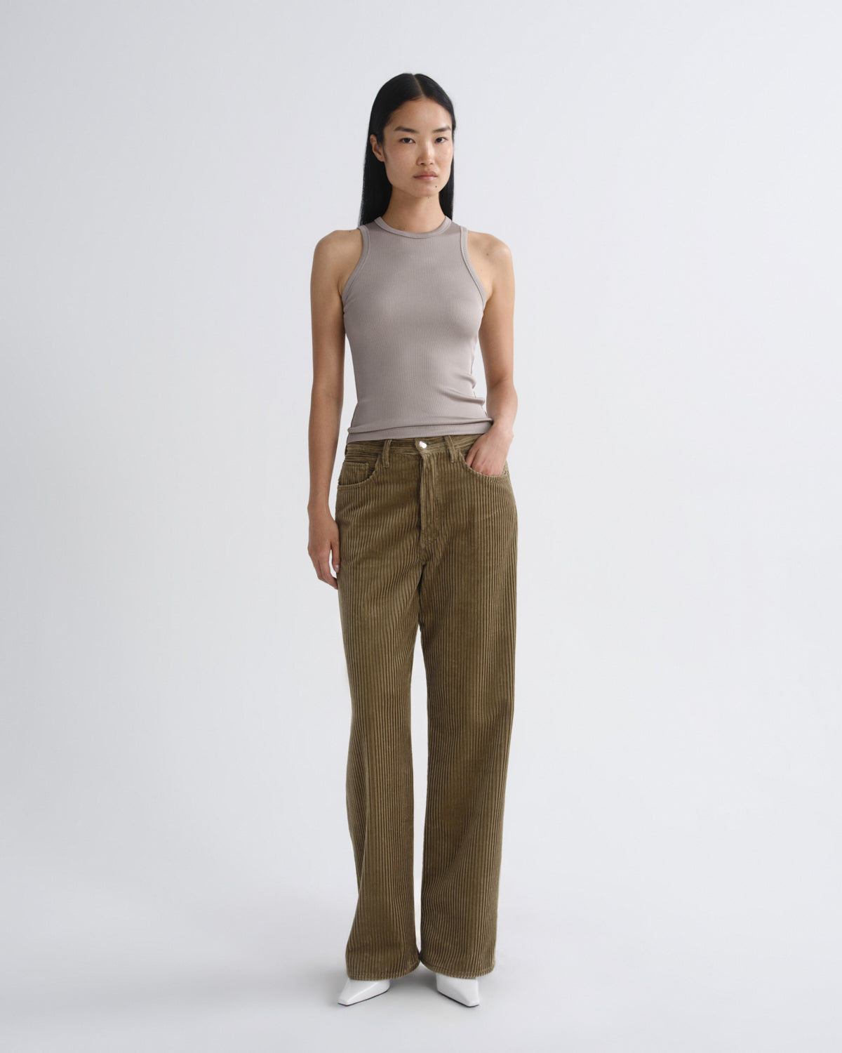 Woman wearing a sleeveless top and brown pants on a white background