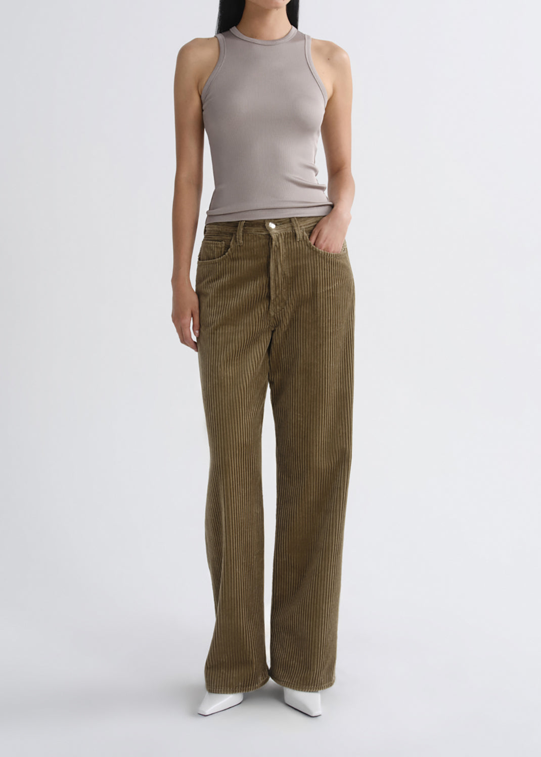 A model wearing a sleeveless taupe ribbed top and olive-brown wide-leg corduroy pants, standing against a grey background.