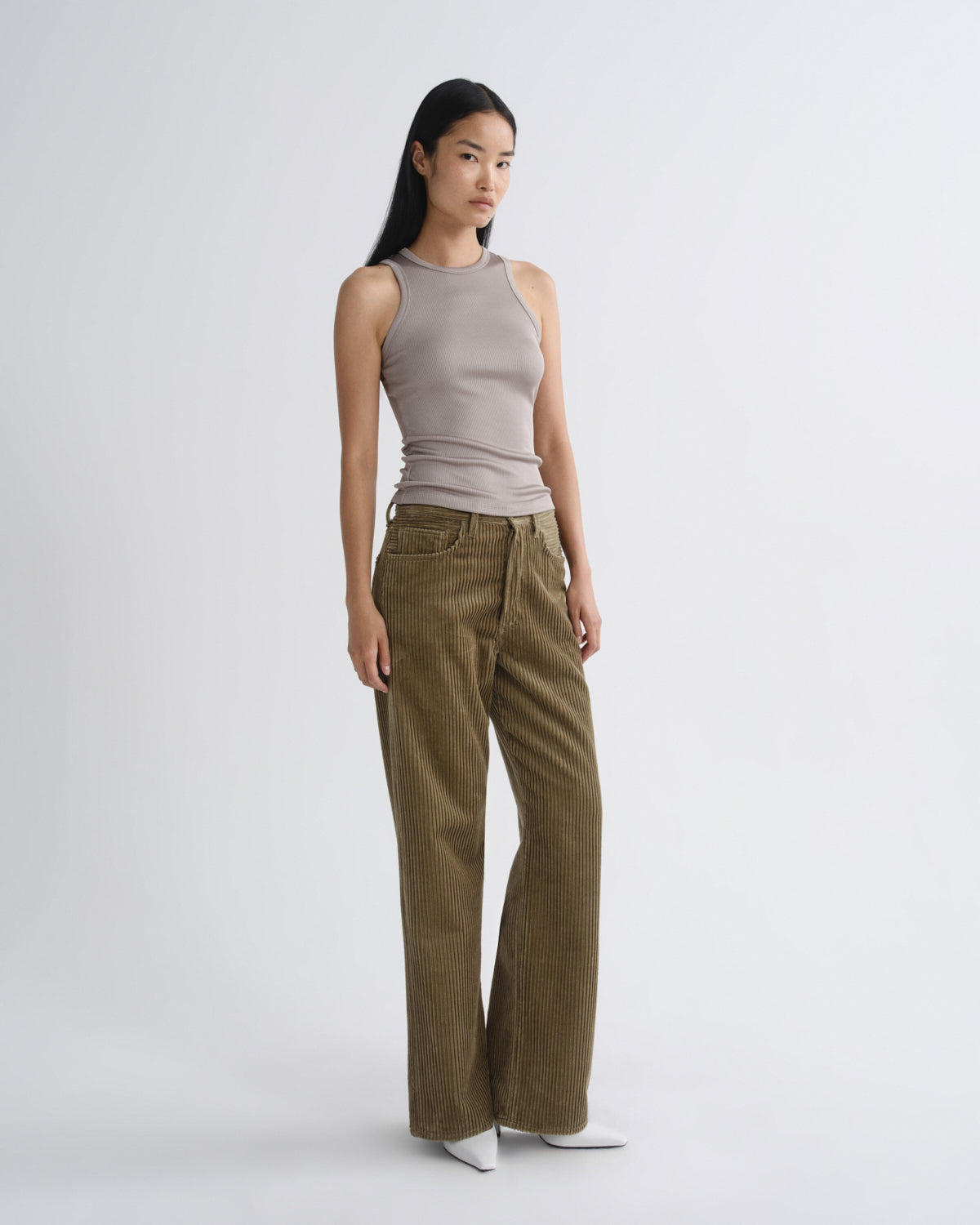 Woman wearing a sleeveless top and brown pants on a white background