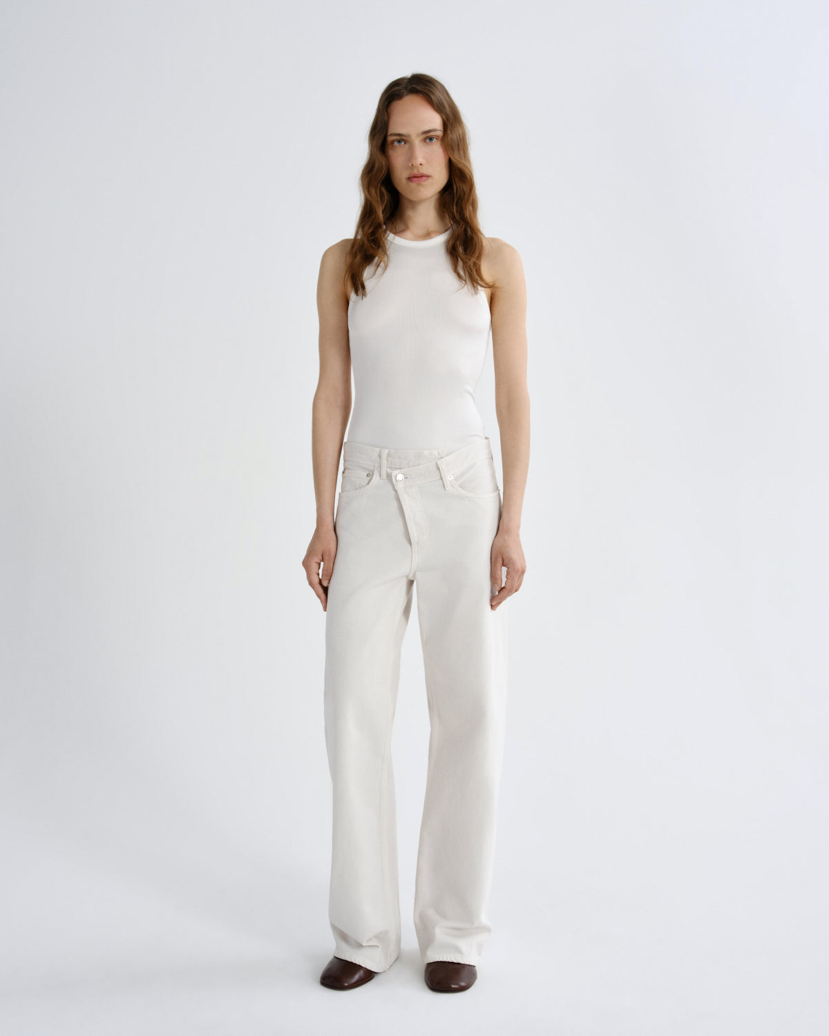 Woman wearing a white sleeveless top and pants on a white background