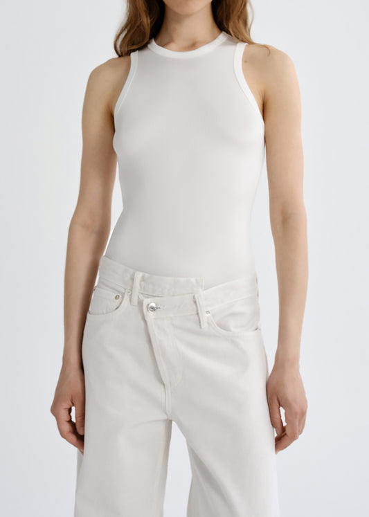 A model wearing a fitted sleeveless white top and white pants against a grey background.