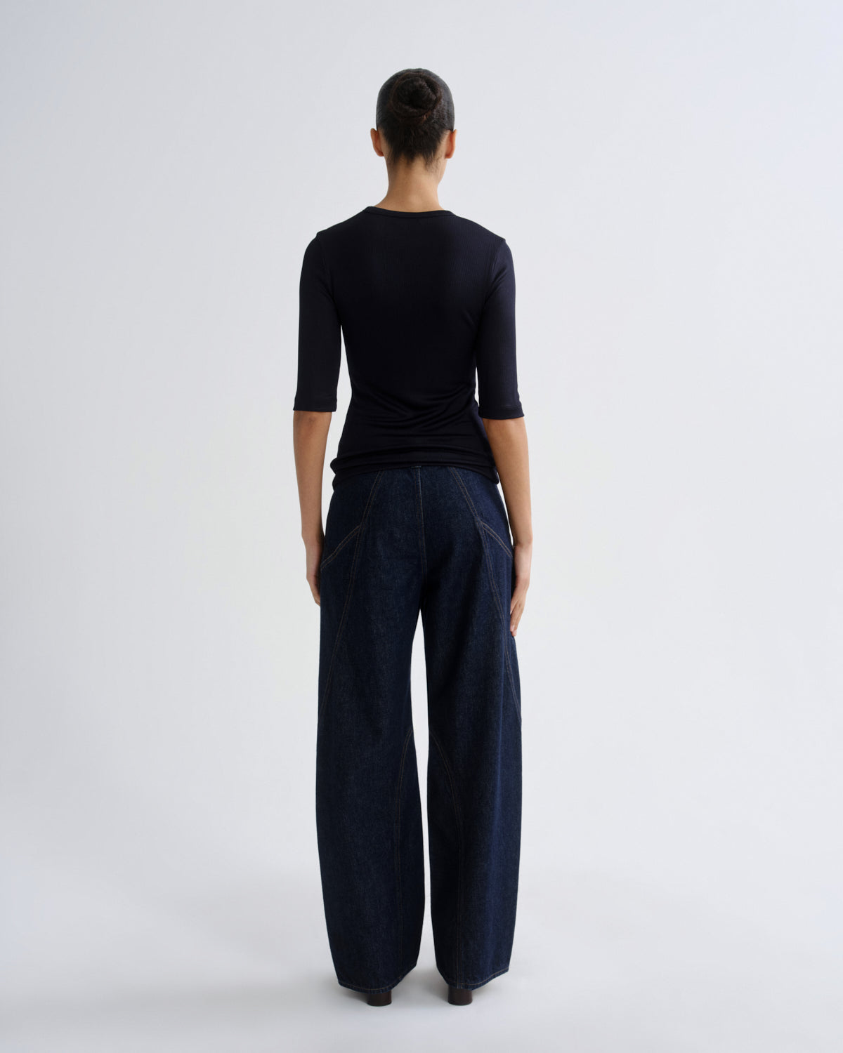Person wearing a black outfit with wide-leg pants on a white background