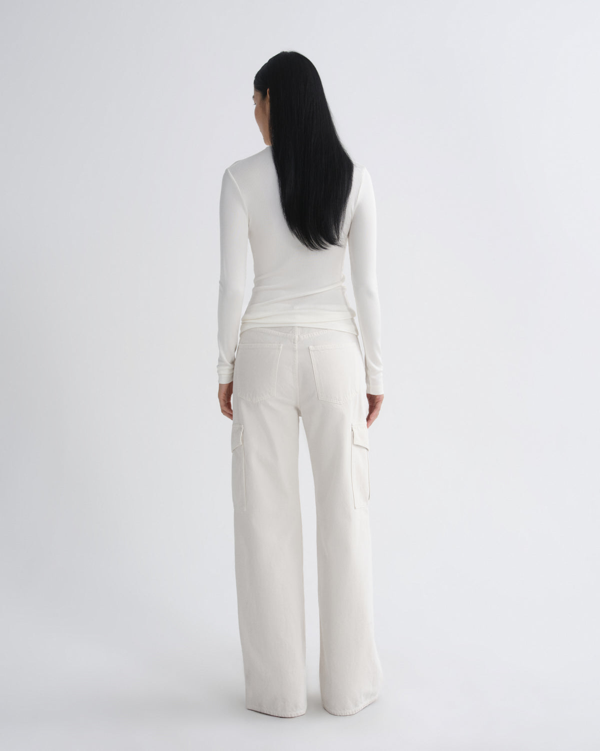 Person wearing a white outfit with wide-leg pants on a light gray background