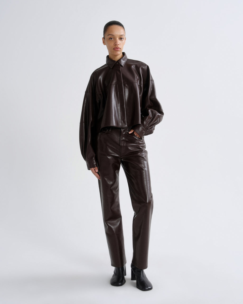 Person wearing a brown leather outfit on a white background