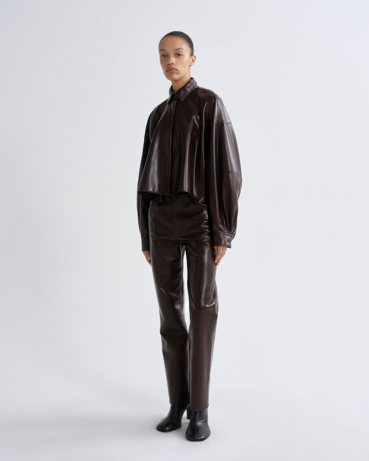 Person wearing a brown leather outfit on a white background