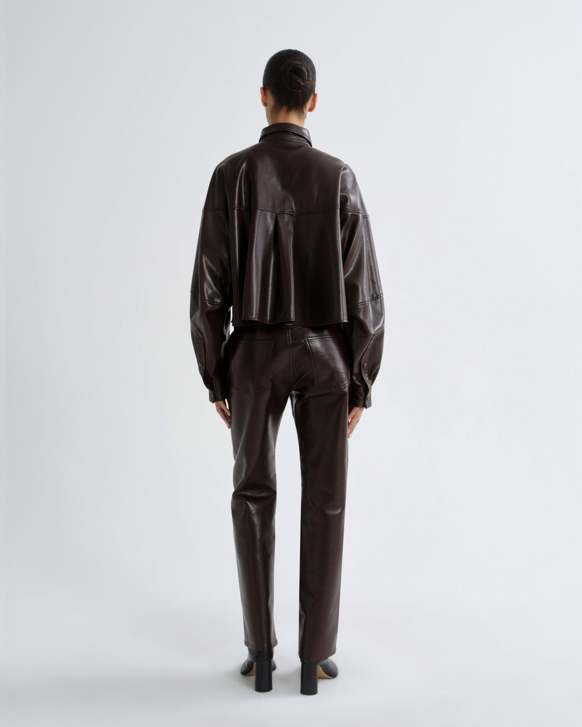Person wearing a brown leather outfit on a white background