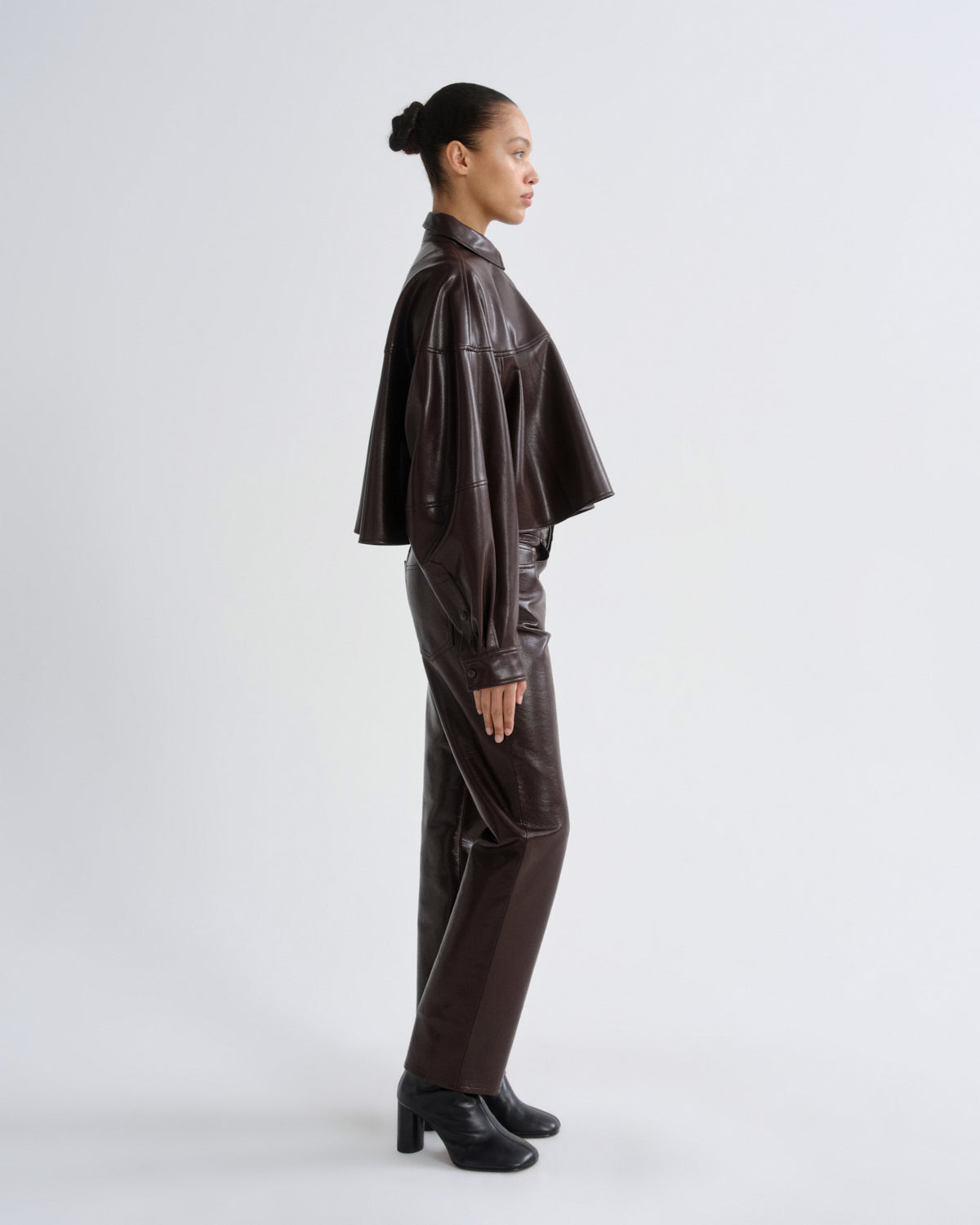 Person wearing a dark brown leather outfit on a white background