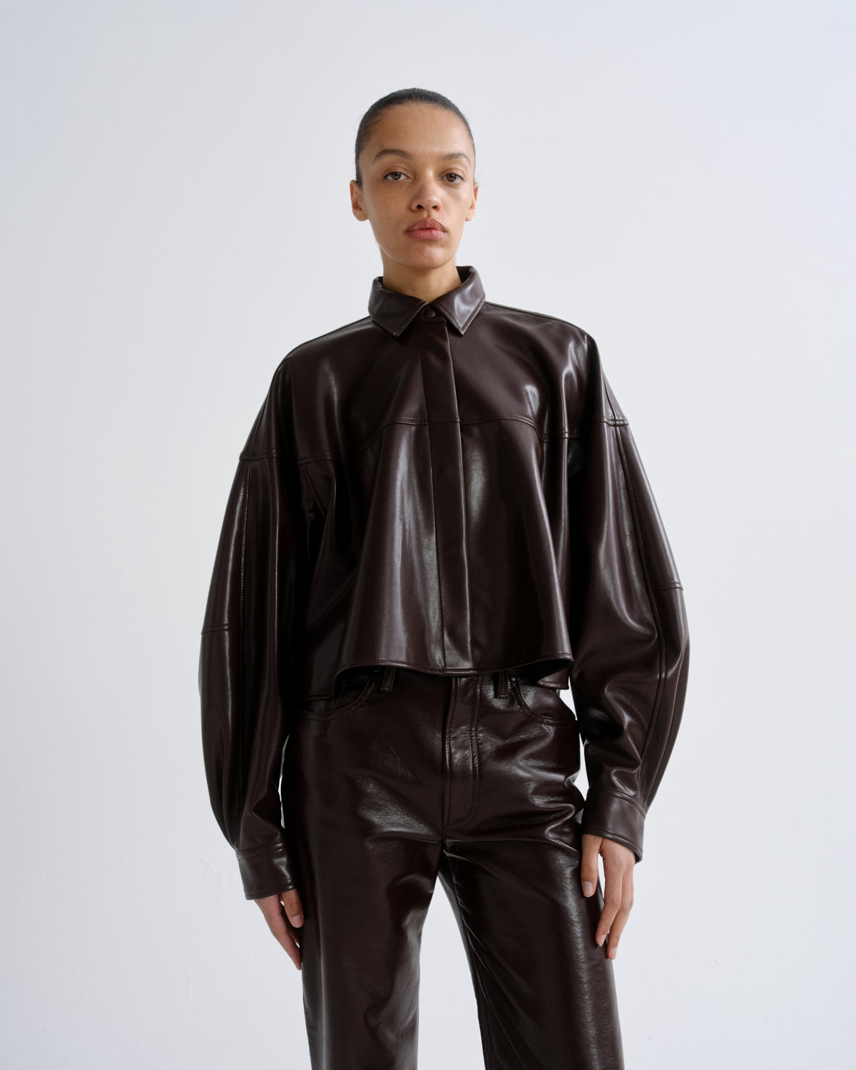 Person wearing a brown leather outfit on a white background