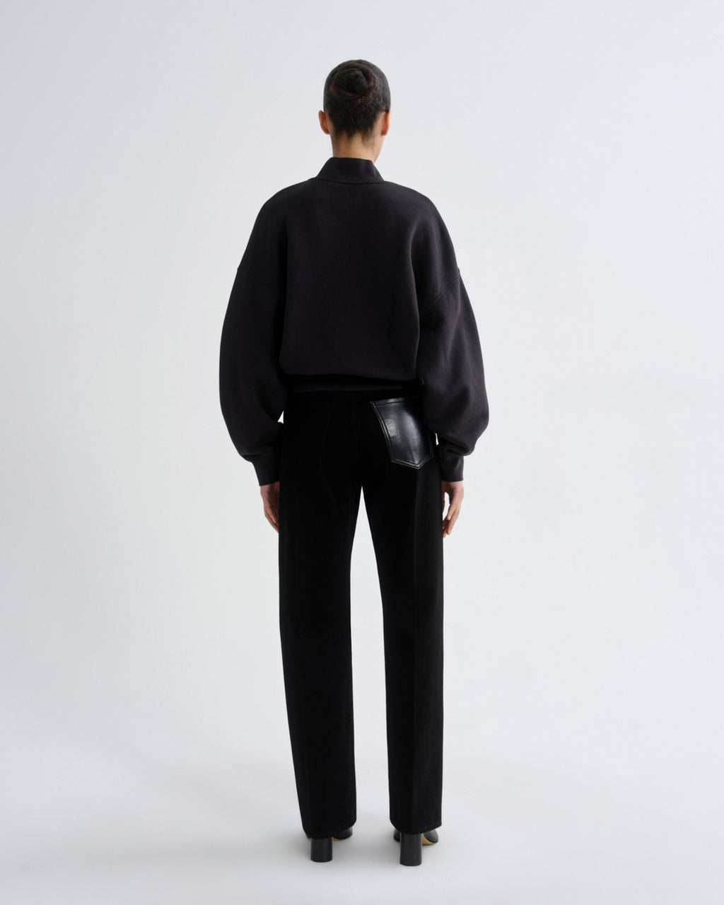 Person wearing a black outfit with a plain white background