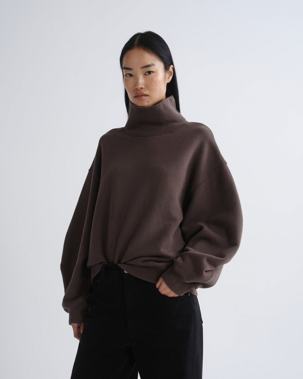 Person wearing a brown turtleneck sweater on a white background