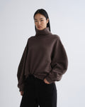 Person wearing a brown turtleneck sweater on a white background