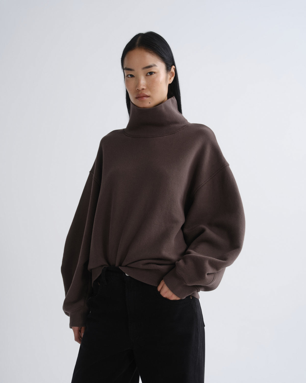 Person wearing a brown turtleneck sweater on a white background