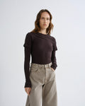 Close up of person wearing brown layered t-shirt with khaki pants on a grey background