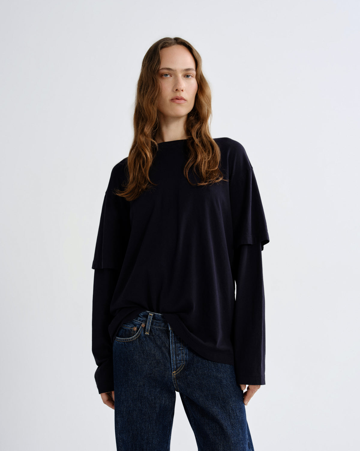 Person wearing a black oversized sweater and blue jeans on a white background