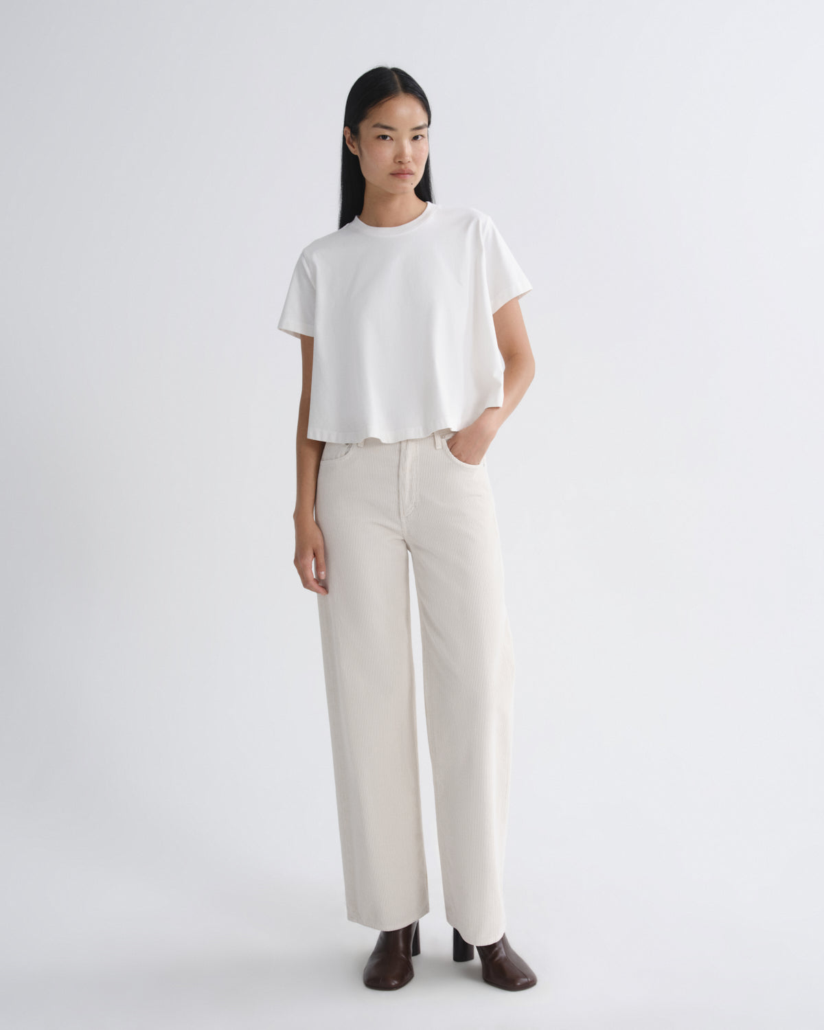 Woman wearing a white t-shirt and beige pants on a plain background