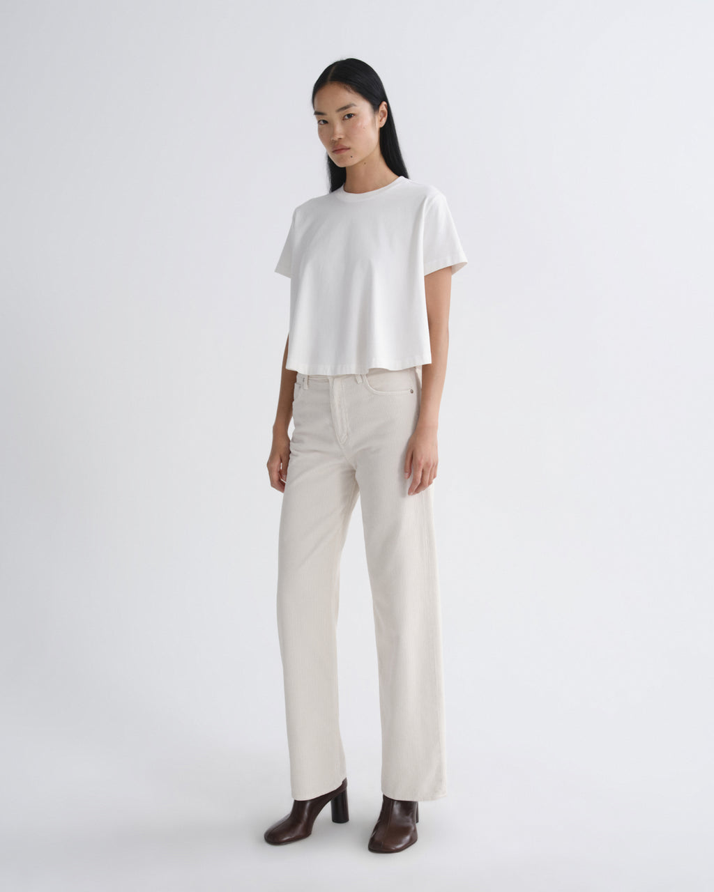 Woman wearing a white top and beige pants on a white background