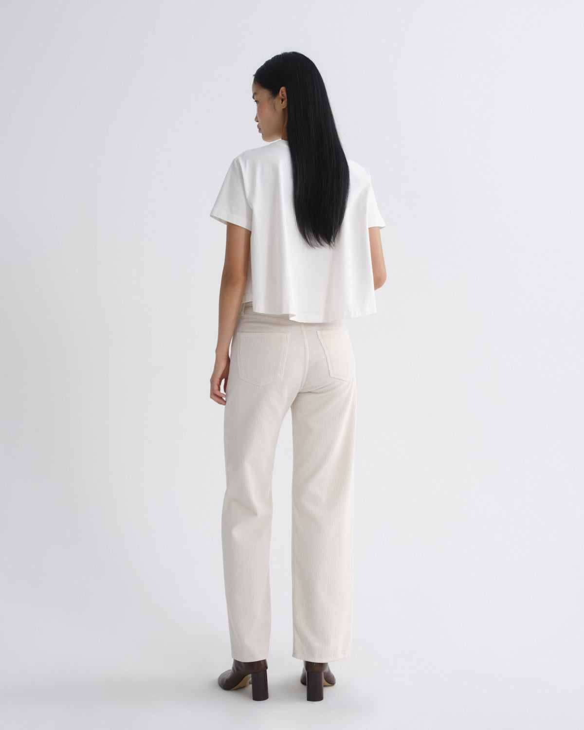 Person wearing a white top and beige pants on a plain background