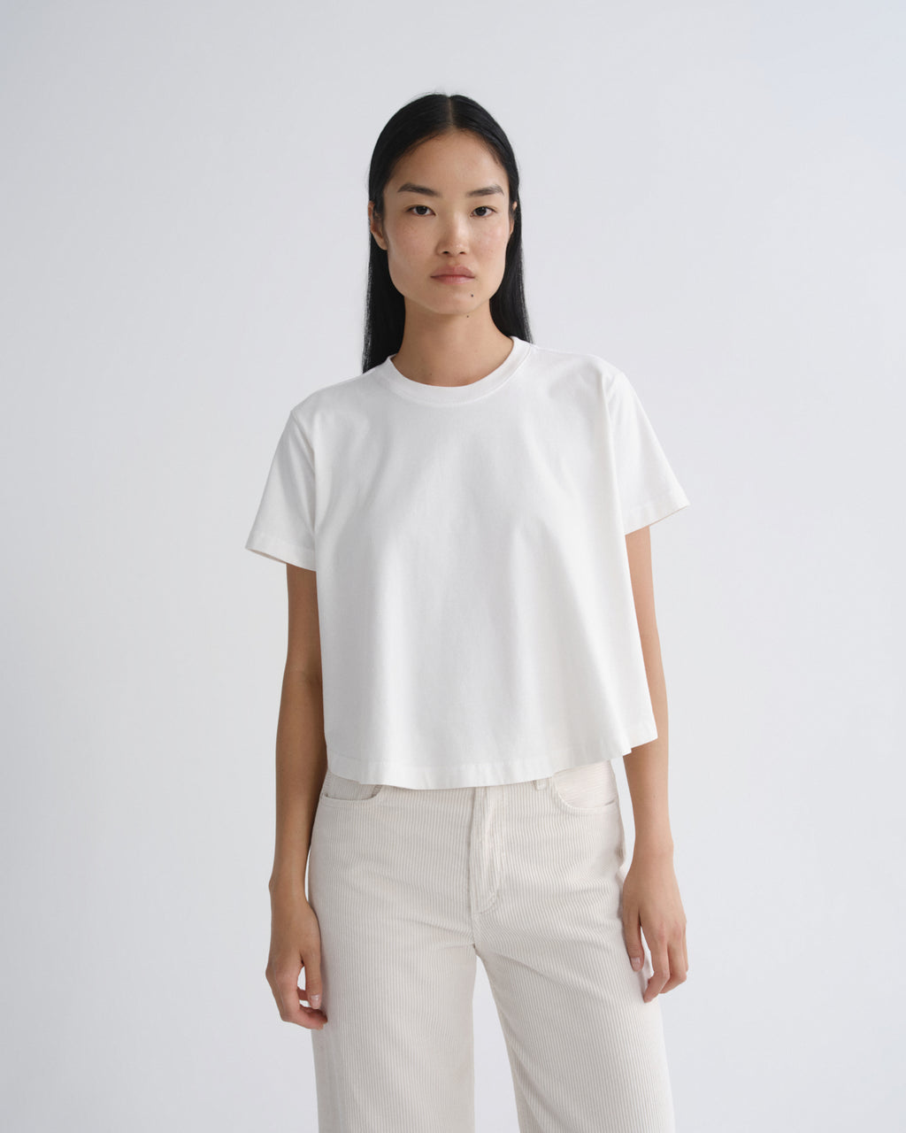 Person wearing a white t-shirt and light-colored pants on a plain background