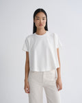 Person wearing a white t-shirt and light-colored pants on a plain background