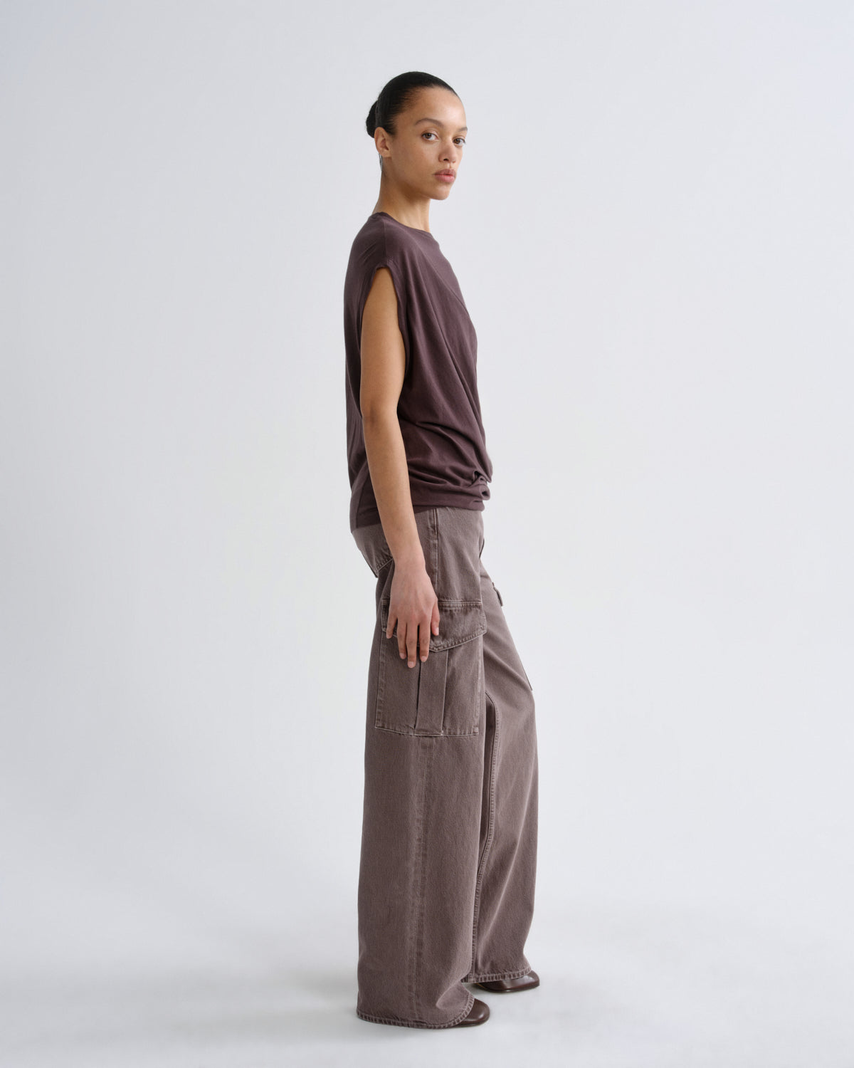 Woman wearing a sleeveless top and wide-leg pants on a grey background