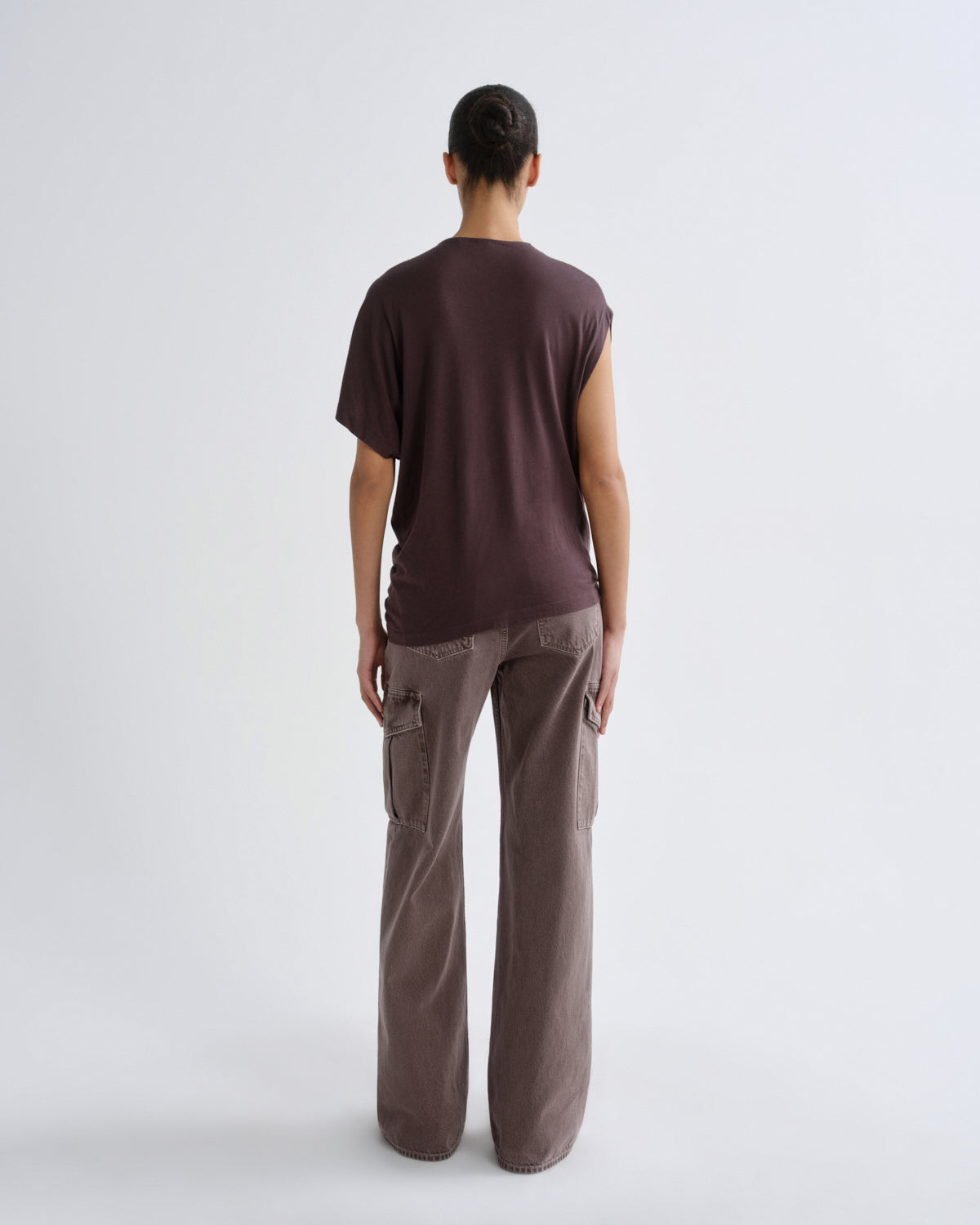 Person wearing a dark purple t-shirt and dark pants on a grey background