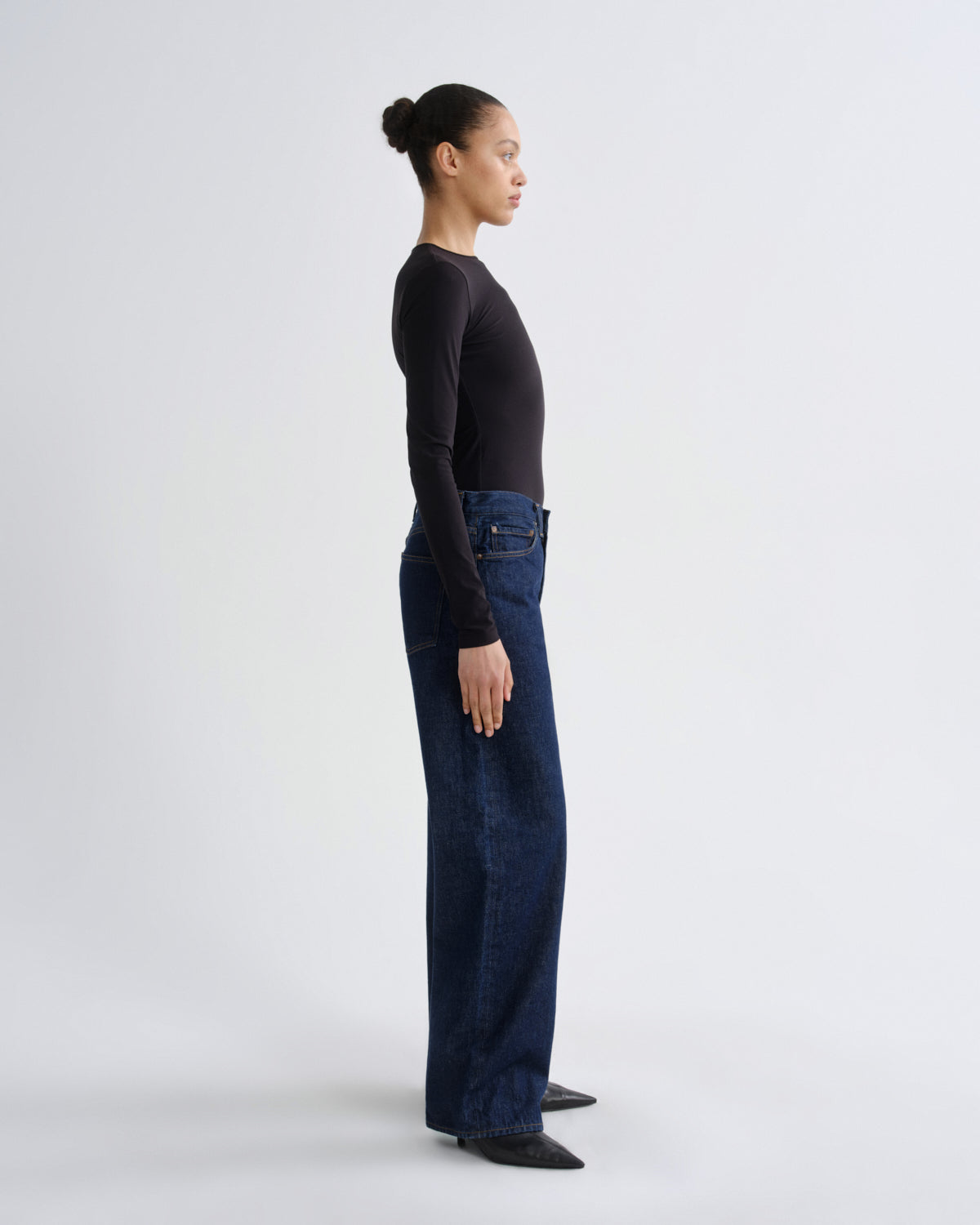 Person wearing dark blue jeans and a black top on a white background