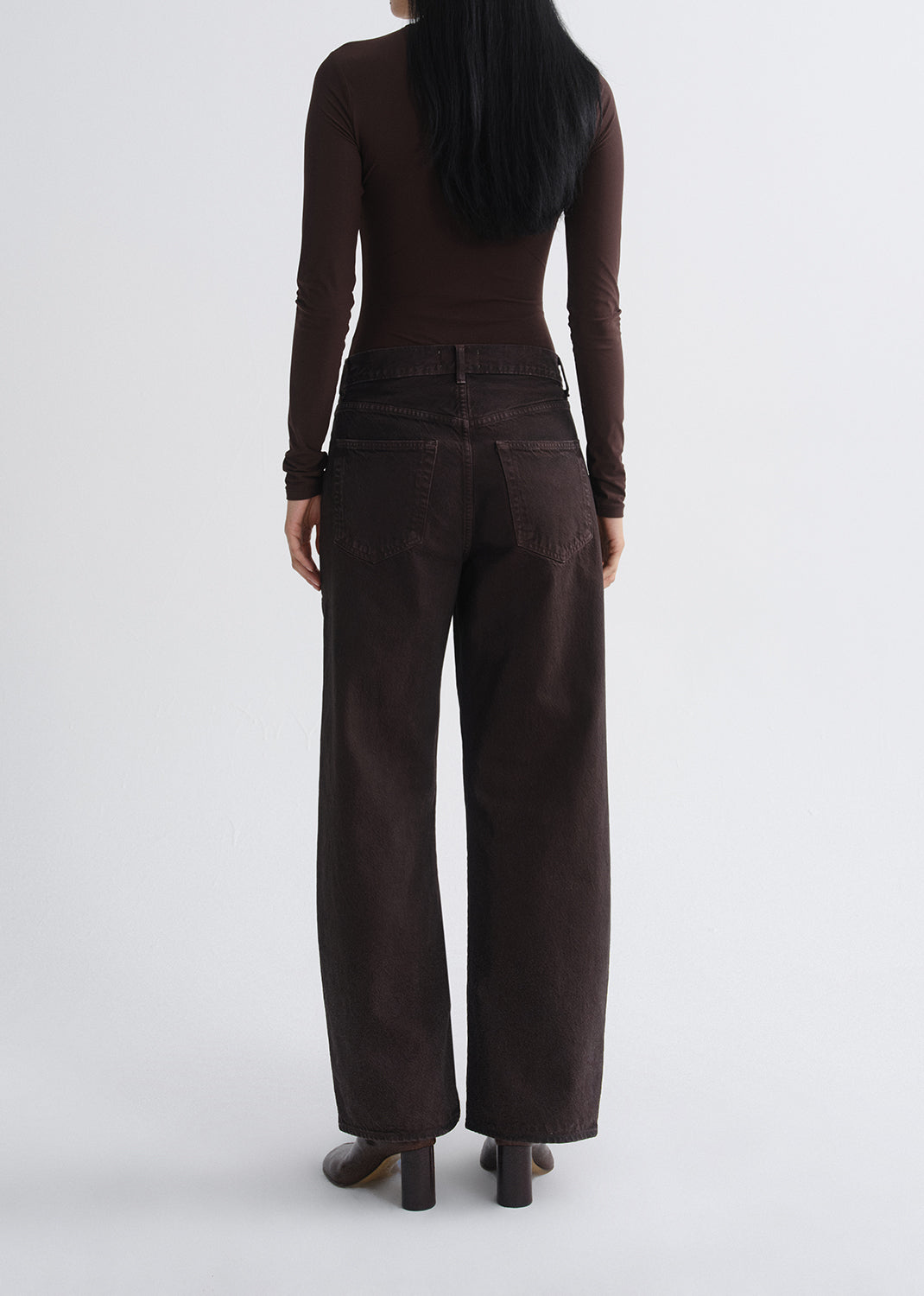 A model shown from the back wearing a dark brown long-sleeve top and matching dark brown wide-leg pants, set against a grey background.