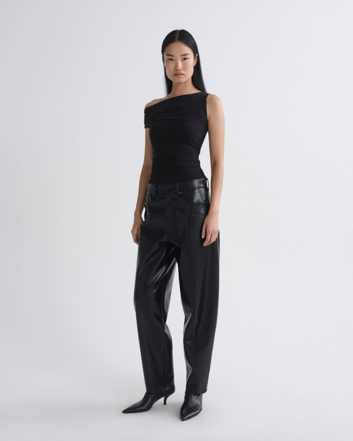 Woman wearing a black outfit with leather accents on a white background