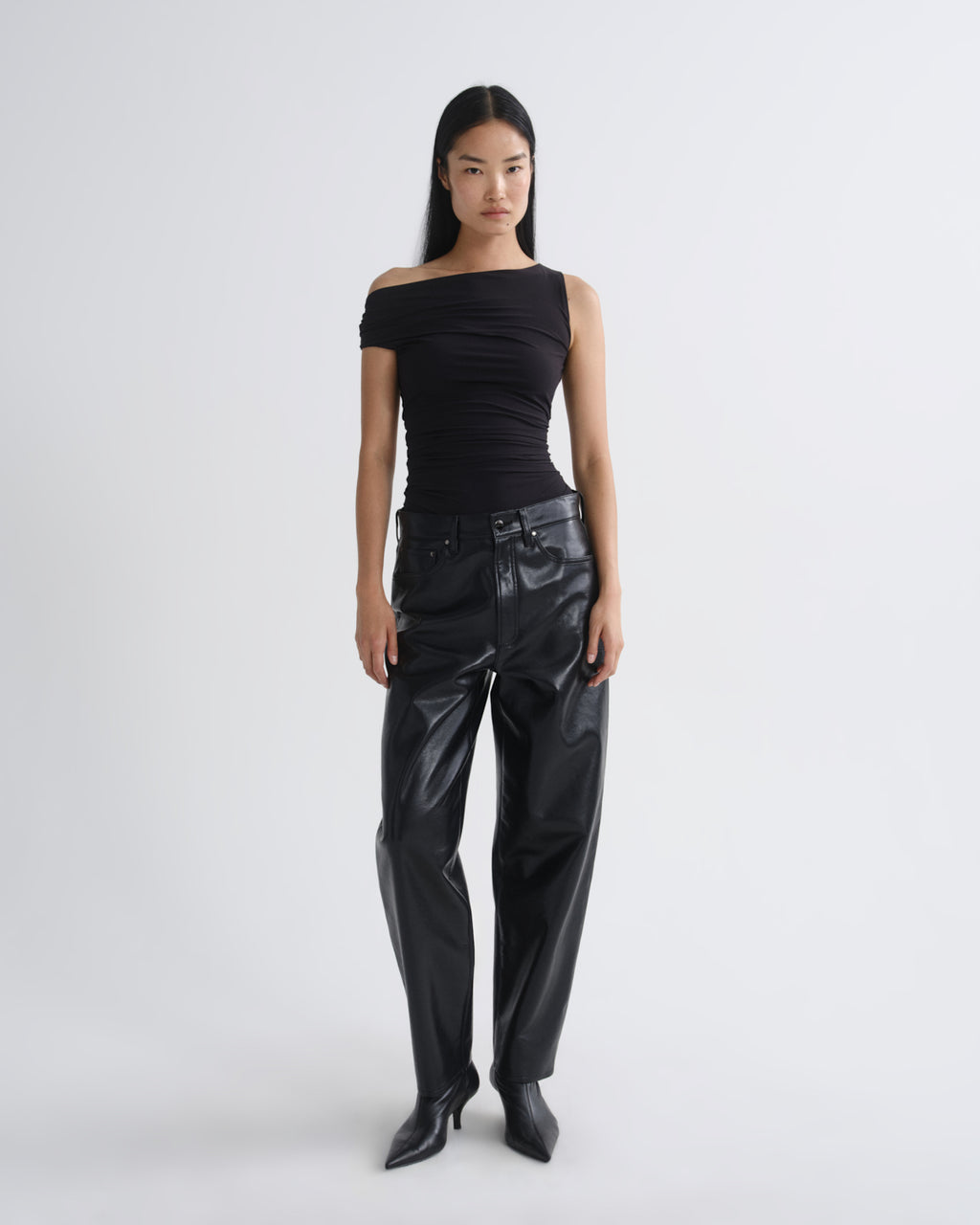 Person wearing a black off-shoulder top and black leather pants on a white background