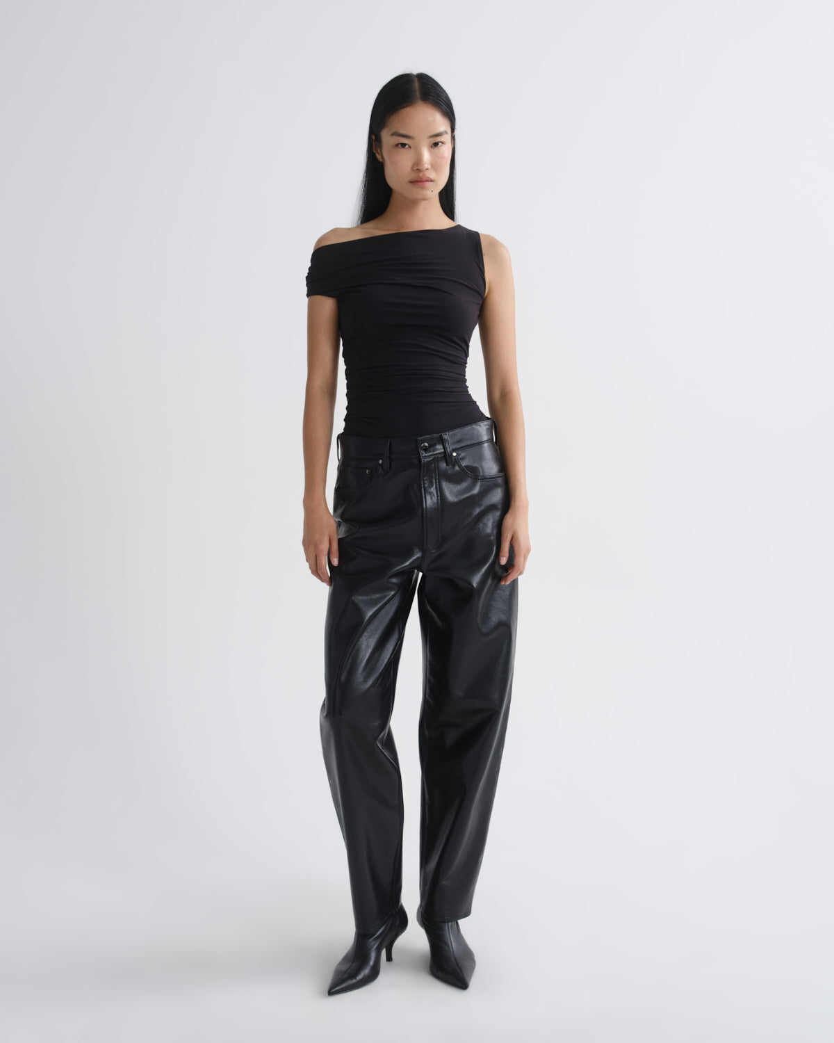 Person wearing a black off-shoulder top and black leather pants on a white background