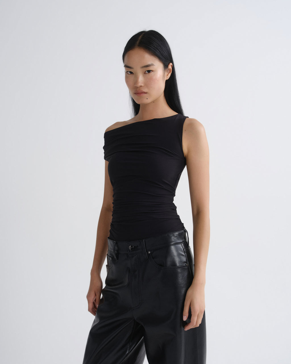 Woman wearing a black one-shoulder top and black pants on a white background