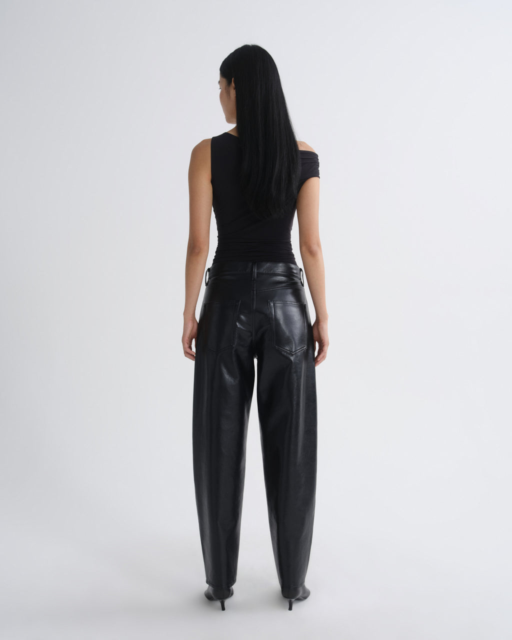 Person wearing black leather pants and a black top on a white background