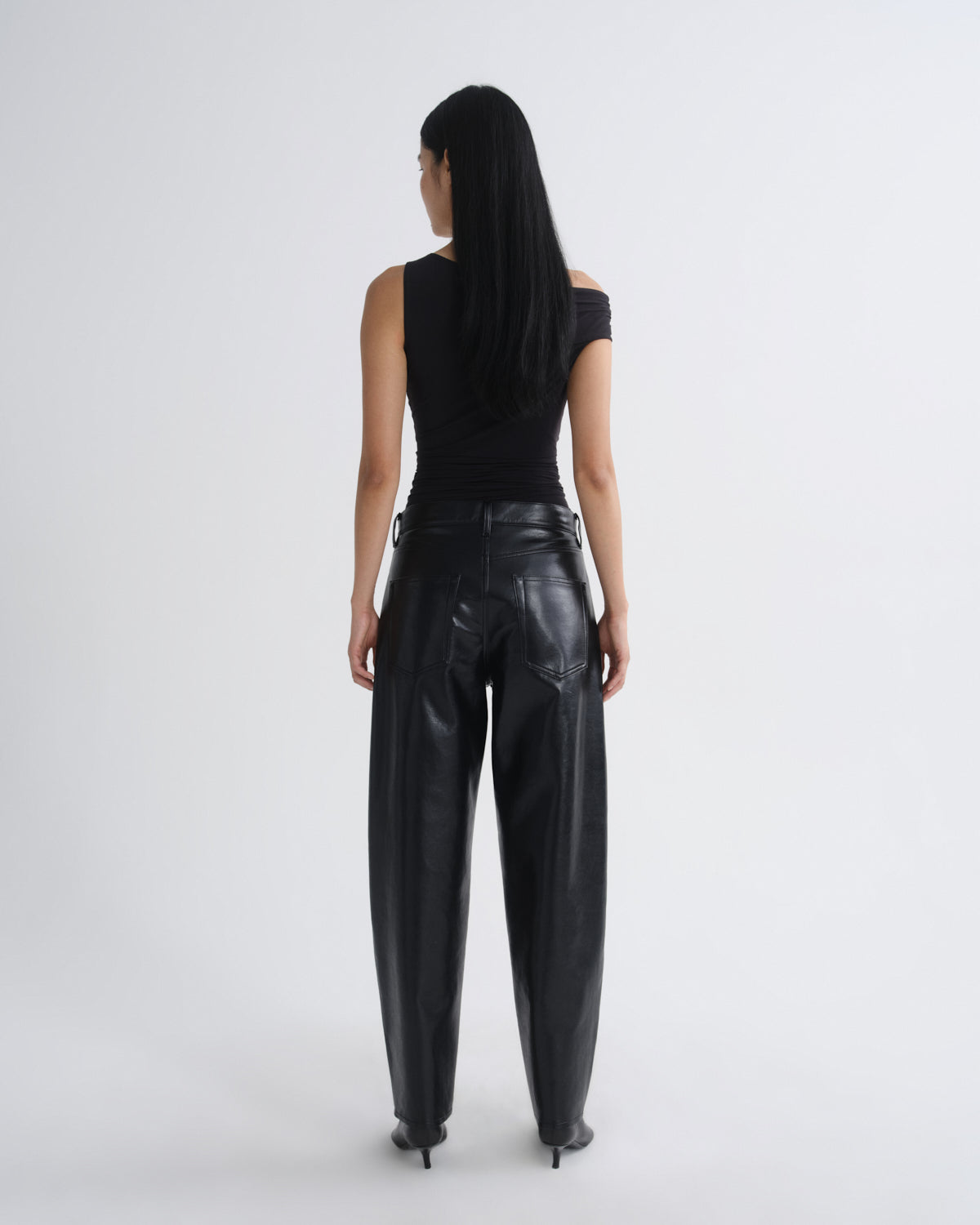 Person wearing black leather pants and a black top on a white background
