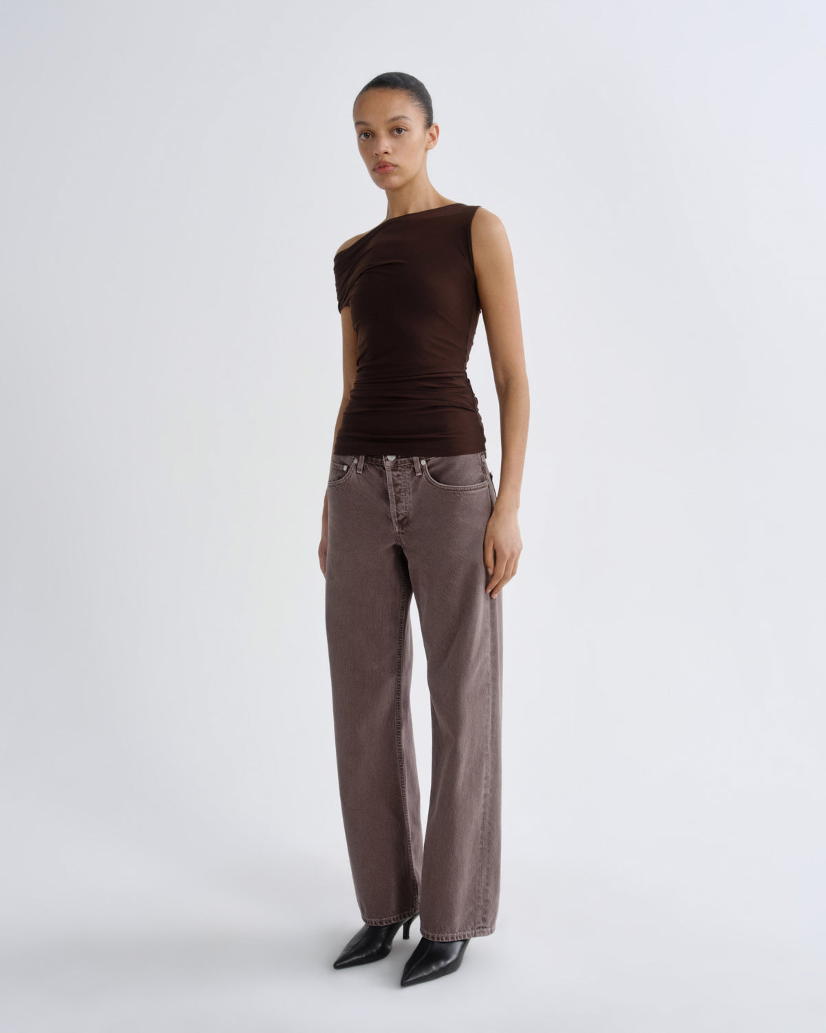 Woman wearing a brown top and pants on a white background