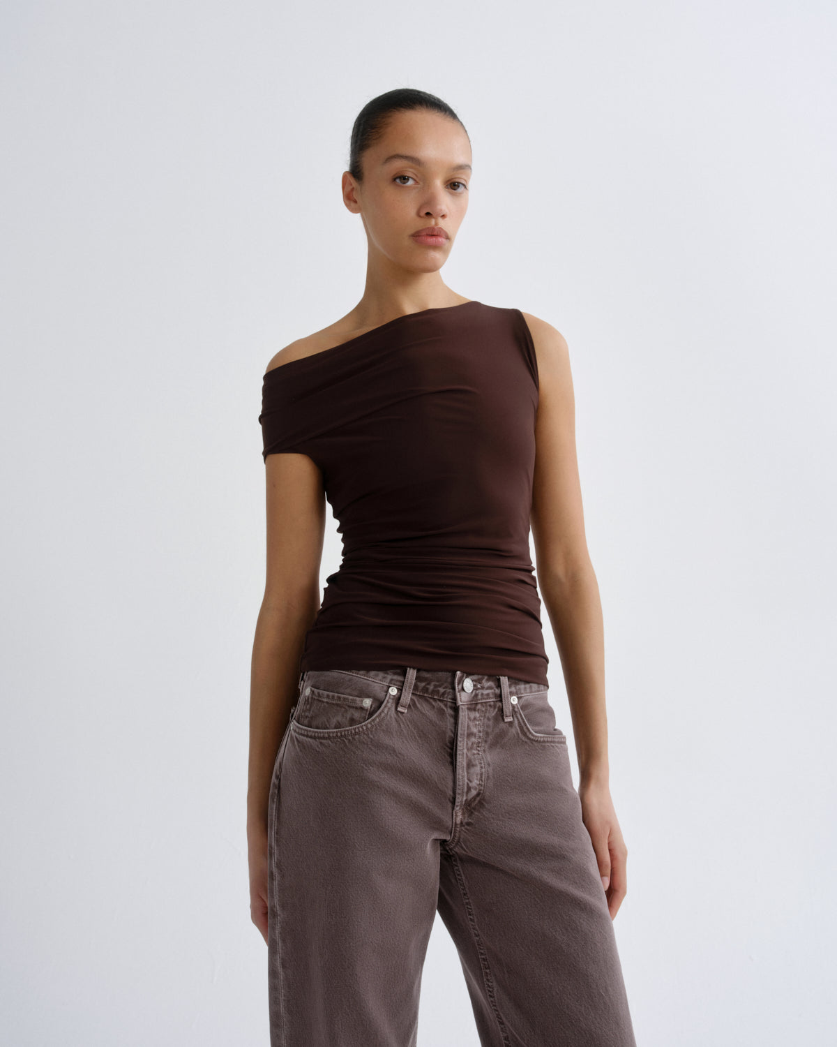 Woman wearing a brown off-shoulder top and matching pants on a white background