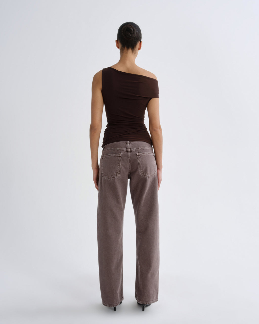 Woman wearing a brown top and light brown pants on a white background
