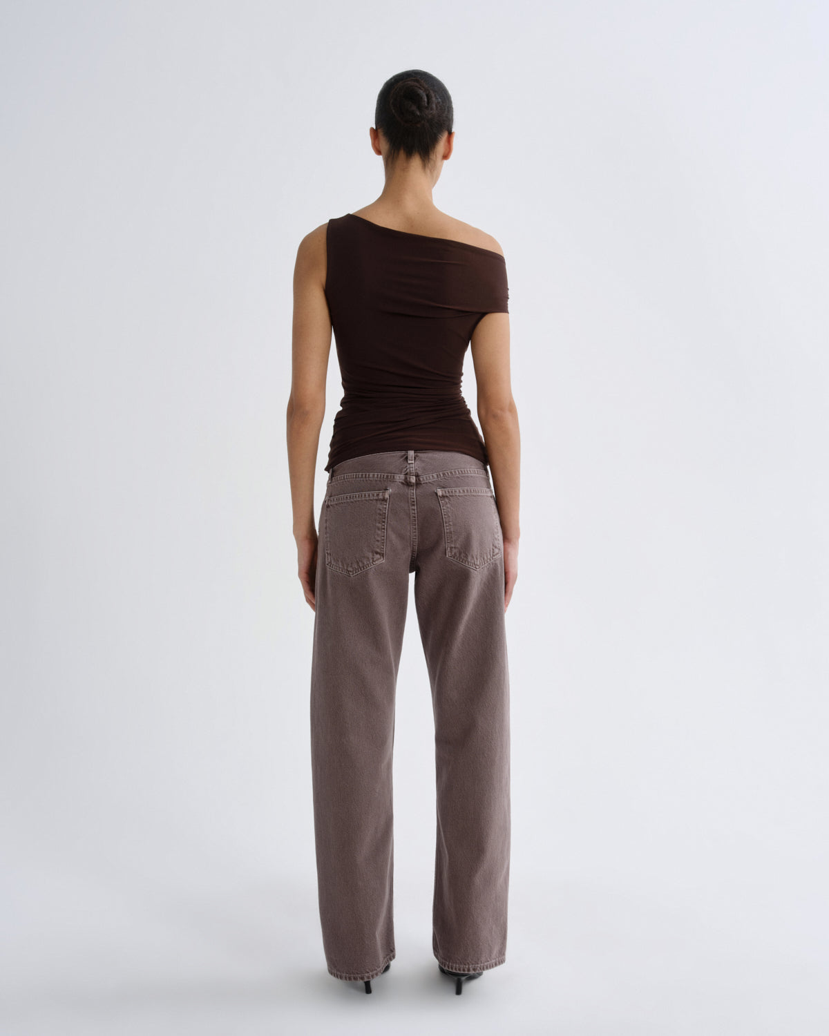 Woman wearing a brown top and light brown pants on a white background